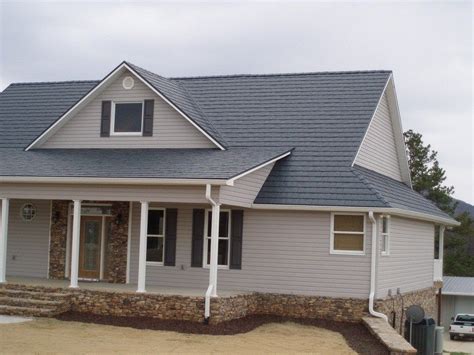 gray house with white shutters and blue metal roof|grey colour paint house outside.